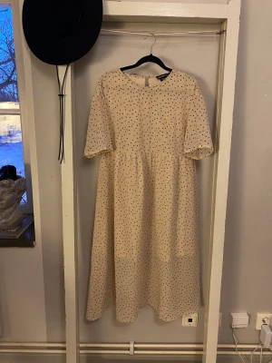 Söt prickig klänning - Söt prickig sommarklänning. Löst sittande modell, T-shirt ärmar och tunt skirt tyg nertill. Använd 1 gång, säljer då den inte riktigt var min stil 🥰 beige rosa färg och svarta prickar, Midi längd 