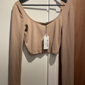 En beige topp - En helt oanvänd tröja ifrån NAKD, den är i storlek S men passar även M, den är kortare i längden, skriv för mer bilder!