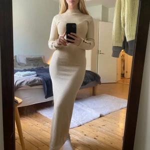 Stickad klänning - Ljus beige lång stickad klänning med slits och dekorativa ”hål”. Supermjuk och stretchig, köptes för flera år sen men knappt använt. Tror att märket är Lindex, men är inte helt 100 då lapparna är bortklippta. Skriv för mer bilder eller funderingar ;)