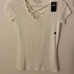 Vit t-shirt med snörning över bröstet, från hollister, aldrig använd och har prislapp kvar, storlek XS