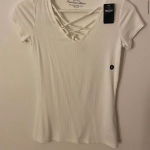T-shirt med snörning - Vit t-shirt med snörning över bröstet, från hollister, aldrig använd och har prislapp kvar, storlek XS