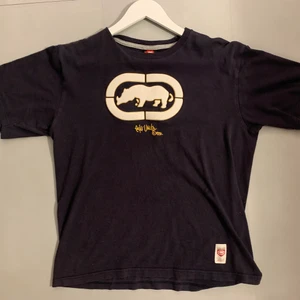 Ecko t-shirt marinblå - Jätte snygg Ecko t-shirt med 3D tryck, och text på baksida. Väldigt bra skick, xl på tagen i barnstorlek men sitter som en M vuxen. Möts upp i centrala Stockholm och kan anars posta.