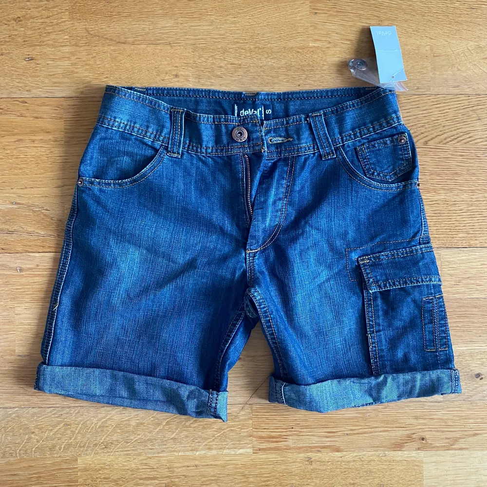 Ett par assnygga Deval cargo demin shorts! Säljer då de är för stora för mig tyvärr 😫 De har bara blivit testade en gång, så de är i toppenskick! ❤️❤️  Jag skulle säga att de är Midrise. De kommer med en extraknapp också, ifall en av knapparna ramlar av ❤️. Shorts.