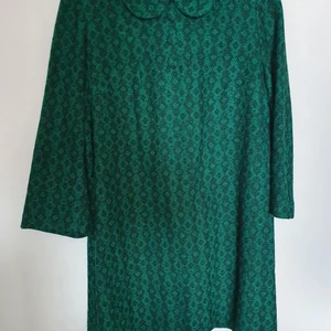 Stickad vintageklänning - Stickad vintageklänning i jättefint skick. Den har en liten krage samt 3 st knappar vid halsen. Skulle säga att den passar både stl M och L. Den är 80 cm lång och 52 cm över bysten.