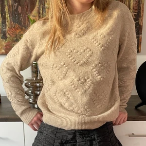 Stickad tröja - Perfekta stickade tröjan från hm med superfina hjärtan på! Är i färgen beige och passar superbra att ha över en klänning, kjol eller till jeans. Använd fåtal gånger💛💛