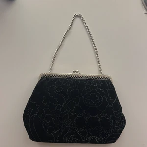 Klassisk svart clutch/miniväska  - Fin clutch i sammet med silvriga detaljer och kedja som tyvärr inte kommit till användning och därför förmodligen passar bättre hos någon annan🥰 Köpt på secondhand för några år sedan och knappt använd. Kolla andra bild för storleksreferens!