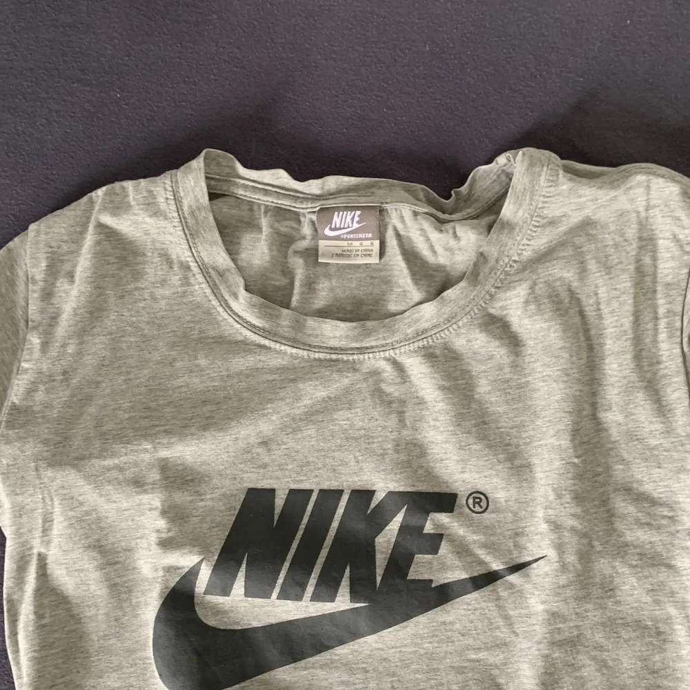 En grå nike t-shirt, med ett niketryck på framsidan. T-shirts.