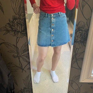 Jeanskjol - En ljusblå jeanskjol i storlek M med knappar, tror att den är från Nelly. Kjolen är i fint skick.