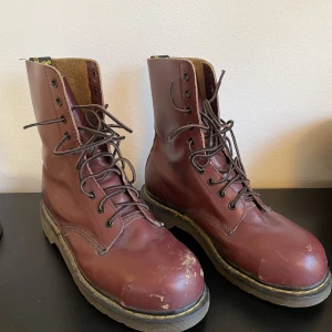 Vintage Dr. Martens - Begagnade höga vintage Dr martens i rött! De är gjorda i England och har stålhätta. De är något slitna på höger sko men annars i ganska bra skick. Storlek 39/40.