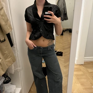 Blus med knapp  - Tröja med knapp i satin.