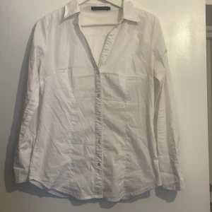 Skjorta - Vit skjorta med detaljerade sömmar och fyrknäppning vid handleden. 