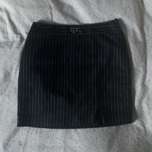Jätte fin svart minikjol - Jättefin minikjol i svart färg med tunna vita linjer. Kjolen har en dragkedja på sidan av den som gör att kjolen sitter tajt och bra! På lappen står det storlek 38 men jag skulle säga att den passa en S oxå:)
