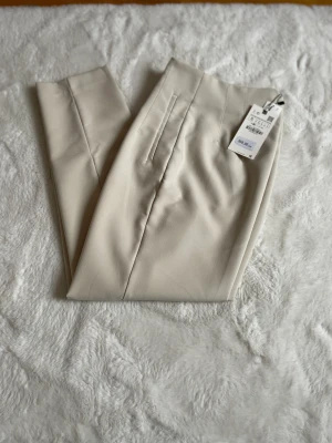 Splitternya byxpr säljer för mycket bra pris - Säljer dessa sandfärgade byxor från zara eftersom jag beställde i flera storlekar men inte hann returnera tillbaka i tid. Helt oanvända, prislapp sitter kvar på, storlek S.  Orginal pris 359kr. Jag säljer för 200. Köparen står för frakten. 