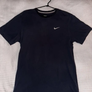 Nike t-shirt - I gott skick.  T-shirten har en modern design med Nike-loggan tryckt på bröstet, vilket ger den en sportig och cool look. Den har också en rund halsringning och en avslappnad passform som gör den lätt att bära vid olika tillfällen. 