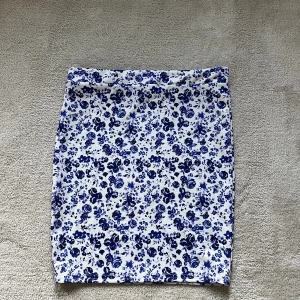 Blommig kjol - Blå och vit blommig kjol från Nelly i nyskick. Tajt passform i stl S.