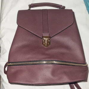 Ryggsäck burgundy - Burgundy-färgad ryggsäck i nyskick. Fin och rymlig. Fejkläder. Hör av dig om du vill ha fler bilder eller om du har frågor!❤️  Höjd: 33 cm (utan handtag).  Bredd: max 36,5 cm.  Djup: 12 cm (mätt från botten). 