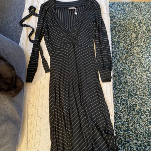 Klänning Jumperfabriken - Svartrandig klänning med silvriga ränder. Storlek 40. Finn passform, ganska urringad. Sparsamt använd.