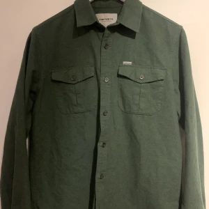 Carharrt skjorta - Superfin och skön skjorta. 100% bomull Nyskick, använd 2ggr. Säljes pga vuxit ur den. Passar tonårig kille eller tjej med storlek S/M .  Nypris 1100kr. Köpte den förra vintern.