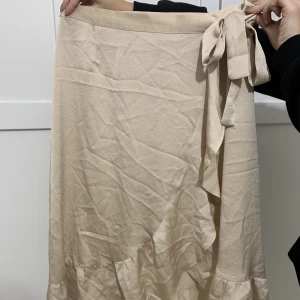 Kjol i satin  - Omlottkjol i satinmaterial från neo nior. Guldig färg som är superfin. Behöver bara strykas.