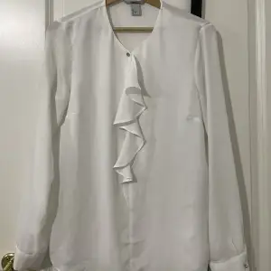 En vit skjorta/blus som är detaljerad på framsidan men lite genomskinlig på baksidan. Dock inte genomskinlig på framsidan. Den är av silk och köpt på hm. Har bytt stil så den funkar inte på mig.