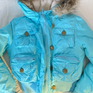 Jennifer Lopez jacka - 2000s JLO kort pufferjacka, strlk S. Använd men i mycket bra skick!  Finns lite lösa trådar i fickorna, en av knapparna på framsidan är lite rostig (saknar färg)  Pälsen är abtagbar på luvan. Om många är intresserade blir det budgivning 😊 