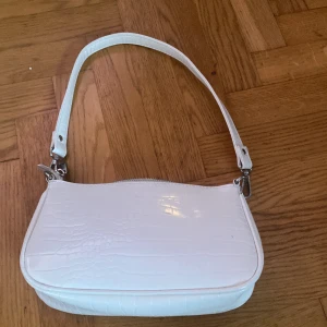 Väska  - Jag säljer min vita väska för den kommer inte till andvändnig.Den är från Gina tricot.Den har en liten ficka i väskan.