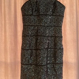 Fest klänning - Kort, off shoulder klänning. Svart & glittrig. Helt oanvänd köpt i NY men slutade med att den bara blev provad hemma & sen hängt i garderoben.