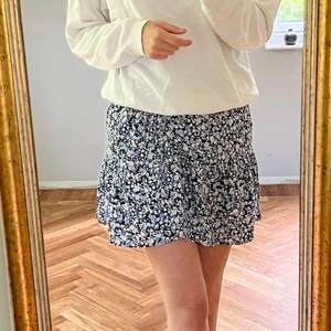 Blommig kjol i färgerna blå/vit och svart. Modellen är medium-kort och passar perfekt på mig som är 176cm. Ganska tajt i midjan men väldigt strechig så passar alla från Xs- M beroende på hur man vill att den sitter, jag är normalt sett en S