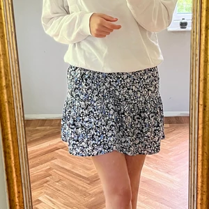 Blå/vit/svart skjol - Blommig kjol i färgerna blå/vit och svart. Modellen är medium-kort och passar perfekt på mig som är 176cm. Ganska tajt i midjan men väldigt strechig så passar alla från Xs- M beroende på hur man vill att den sitter, jag är normalt sett en S