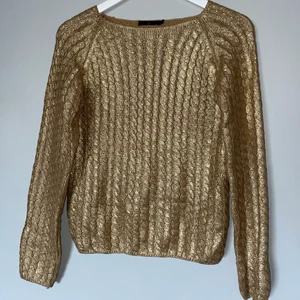 Tröja i guldfärg, ribbad. - ”Stickad” tröja i guld. Tung och rejäl i tyget.