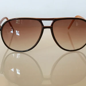 Pilot solglasögon  - Svarta och gulbruna solglasögon, tunn och lätt båge, rätt så stor i modellen.