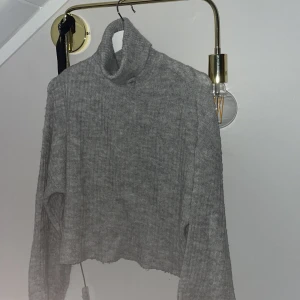 Stickad tröja med polo  - En stickad ljusgrå polo tröja med trumpet armar. Ärmarna på tröjan går att vika upp och dom är ganska långa, annars ganska bra skick skriv för mer funderingar 