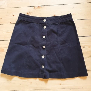 Minikjol - Svart minikjol med knappar fram ifrån H&M🥰 Aldrig använd, prislapp kvar. Storlek 36, midjemått ca 72 cm, Längd ca 42 cm. Bara att skriva om du har några funderingar