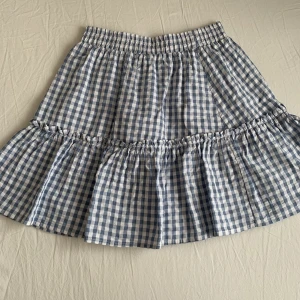 Kjol - Fin somrig kjol i ett vitt och ljusblått rutit mönster, sparsamt använd och super fint skick! Från NA-KD, st 34 Hör av dig om fler frågor eller intresse!