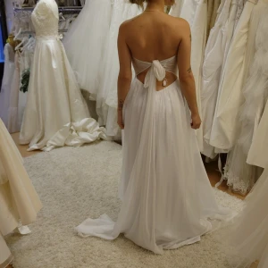 Brudklänning  - Köpte en annan så säljer nu denna. Väldigt lätt, svalt tyg. Skulle passa perfekt på en strand om det ger en känsla. Passar nog allt från xs till m eftersom den knyts i ryggen. Jag är 163 och den är inte uppsydd. Finns 10-15 cm till godo 