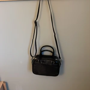 Handväska  - Handväska i svart ormskinnmaterial. Aldrig använd☺️