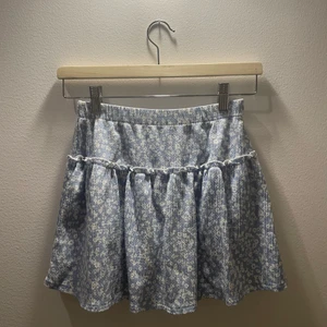Volang kjol  - En jättefin ljus blå volang kjol från zara. Den har ett jättefint blommigt mönster. Kjolen har också inbyggda shorts :)