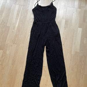 En svart jumpsuit i storlek S ifrån H&M. Otroligt svalt material och lite tunnare band. Längden är 154 cm och fler bilder kan fås! Kan skickas