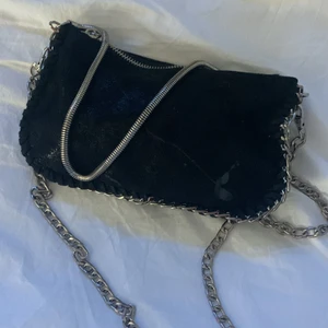 Väska svart med kedja - Säljer denna fina väska köpt för 197 kr och är använd men inga större skador än lite baglack på (kedjan som hänger är trasig så den finns inte på vöskan)