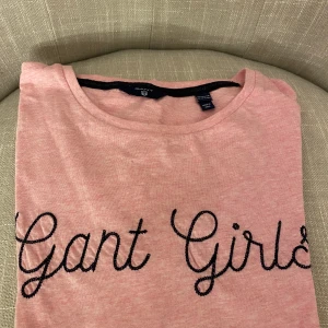 Gant Girls T-shirt - En supersöt Gant Girls T-shirt, rosa med mörkblå text. Är i storlek 158/164 men sitter som en xs/s. Nypris: 400kr, säljer för 75kr. 