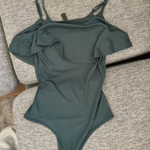 Body med volang  - Grön body med volang. Passar S och M. Passar även om man har längre överkropp. 
