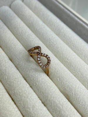 Ring i rose med stenar - En ring i rosefärg med glittriga stenar, ringen har en form i oändlighetstecknet. Fråga om storlek i cm vid intresse 🥰Men skulle säga small- medium ❣️ Fint skick FRAKT 12 KR