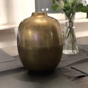 En vas i guld färg med fina mönster. Köpt på Mio. I fint skick Material:  Järn 28 cm i höjd