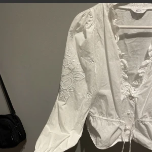 Blus från ENVII strl S  - Fin blus med knytband i midjan samt 3 st knappar. Fina broderier på axlarna och på armarna. Snygg till kjol och till jeans. I gott skick! Strl S
