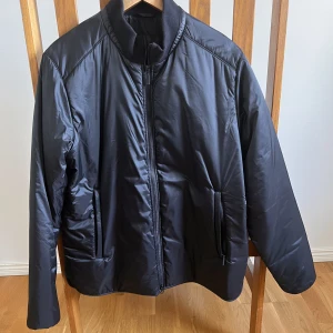 Barbour Jacka svart ( brand new) - Brand new Barbour jacket with two zipped side pockets and one inner pocket. Small discreet  Barbour logo on arm. Size is L with a casual fit. Has some thin padding and makes a perfect spring jacket.