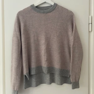 Stickad tröja ull från COS - Grå- och rosamelerad stickad tröja från COS. Är tunn och skön. 72% ull, 16% polyamid, 12% alpacka.