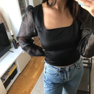 Svart blus ACxNAKD - Fin svart puff sleeve blus från adorable core kollektion med NaKd. Storlek 40. See through ärmar där extraknapp finns med. Diskret dragkedja baktill