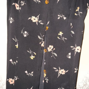 Blommig klänning  - Denna klänning är med knappar och är i storlek M, den har en öppning mitt i fram.