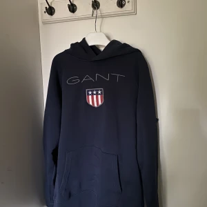Klassisk hoodie av Gant - Oanvänd men etiketten borttagen pga fick den i present. Nypris 899 kr. Fler bilder för äkthetsbevis kan skickas  vid förfrågan. Passar mig som är storlek S vanligtvis. Pris kan diskuteras.