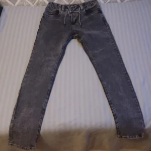 Mörkgrå Jeans - Jeansen är väldig snygga och sköna, de är lite tajta och snören som hänger går att klippas bort om man inte gillar dem 
